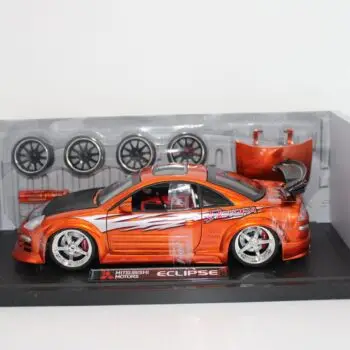 JADA orange Mitsubishi Eclipse diecast racing car in clear plastic packaging with 4 spare tires, hood and a screwdriver.