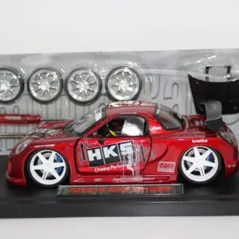 JADA red Import Racer TOYOTA MR2 SPYDER diecast racing car with 4 spare wheels, a screwdriver and a hood in clear plastic packaging.
